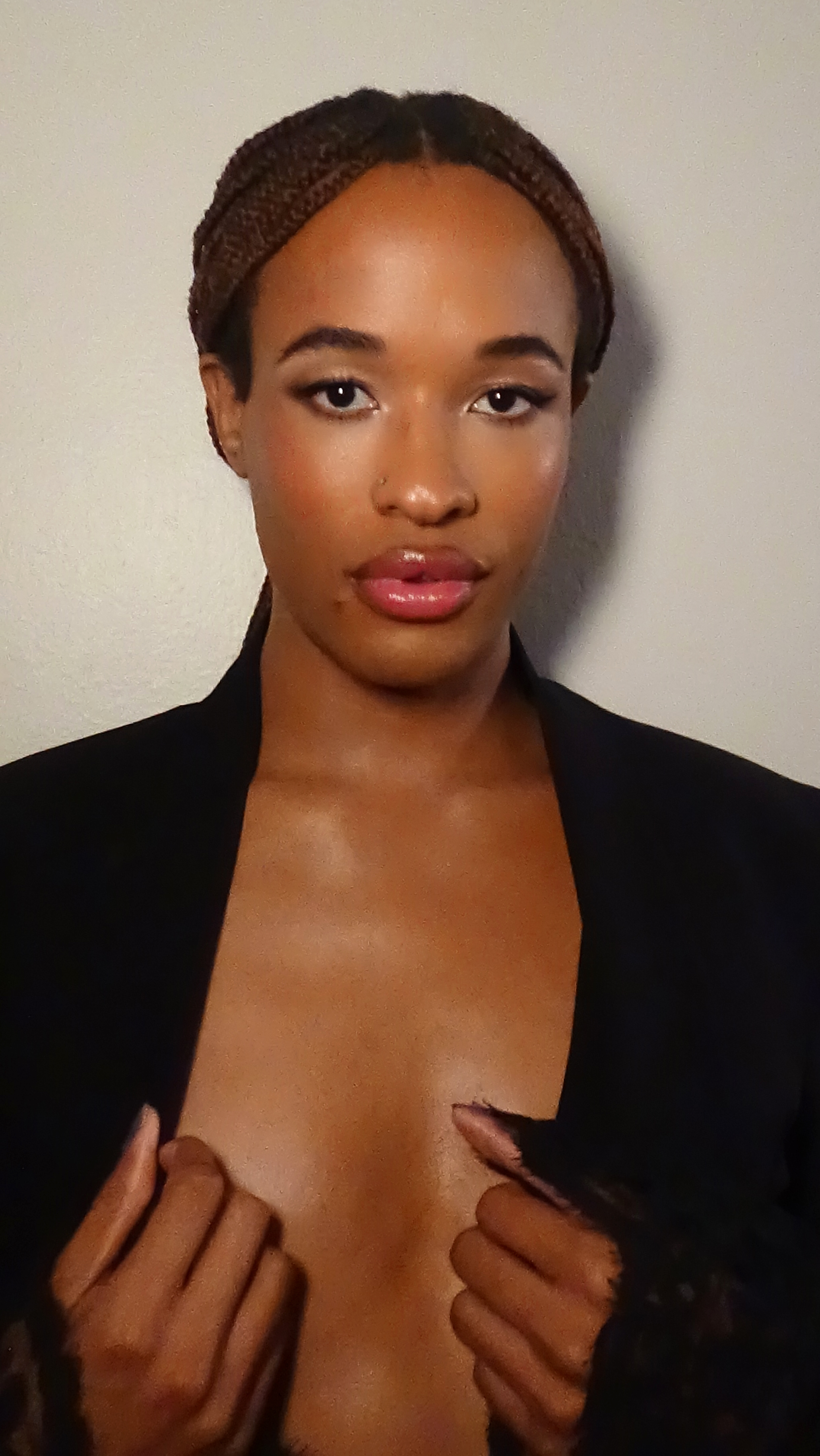 Close up portrait of Jules Crosby with soft glam makeup looking at the camera with her hands on her chest against a white backdrop